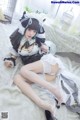 A woman in a maid outfit is laying on a bed.