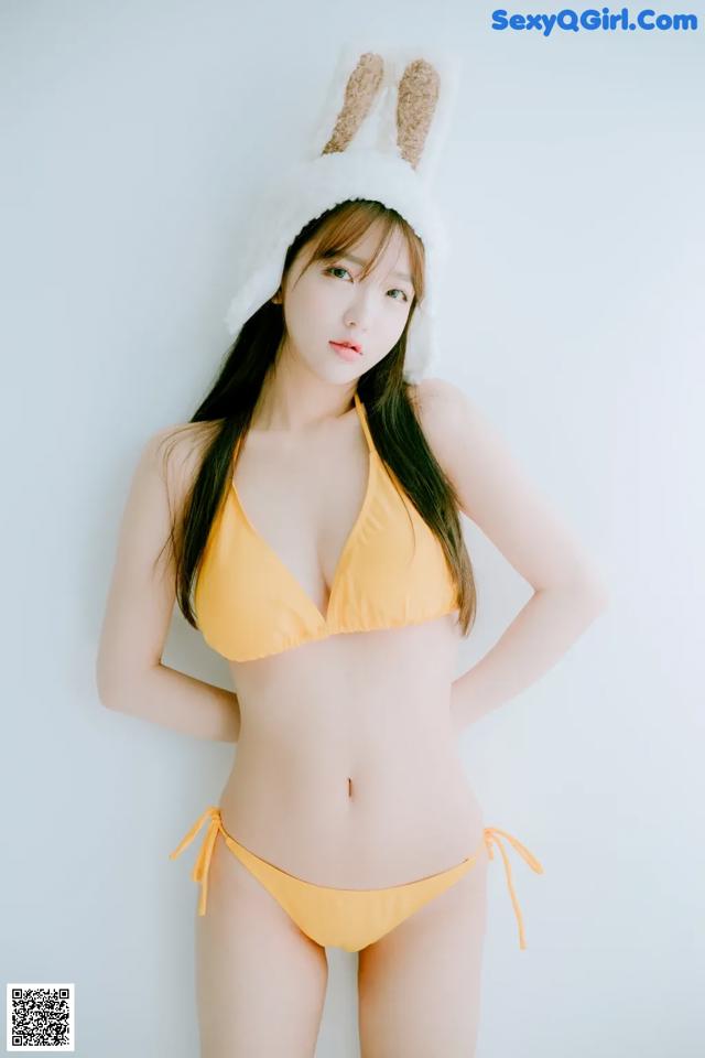 A woman in a yellow bikini and bunny ears.
