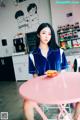 A woman sitting at a pink table in a kitchen.