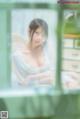 A woman in a white dress sitting on a window sill.