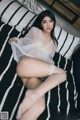 A woman in a white lingerie sitting on a bed.