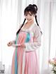 A woman in a pink and blue hanbok is posing for a picture.