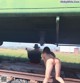 A naked woman sitting on a train track next to a man.