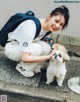 A woman kneeling down with a small dog on a leash.