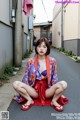 A woman in a kimono sitting on the side of a street.