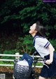 A woman in a school uniform riding a bike.